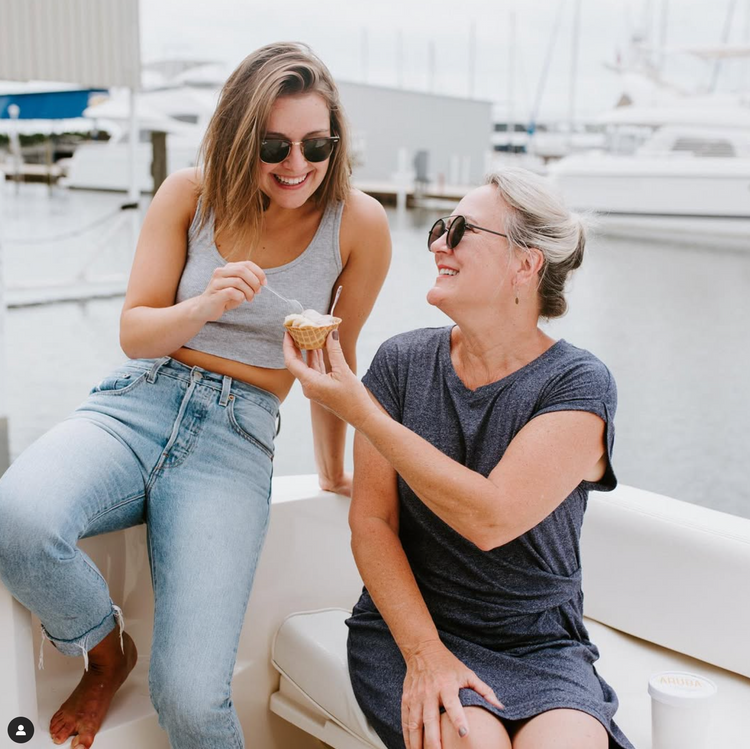 Two women sitting on a dock, enjoying Aruba Freeze Nitrogen Ice Cream and each other's company.